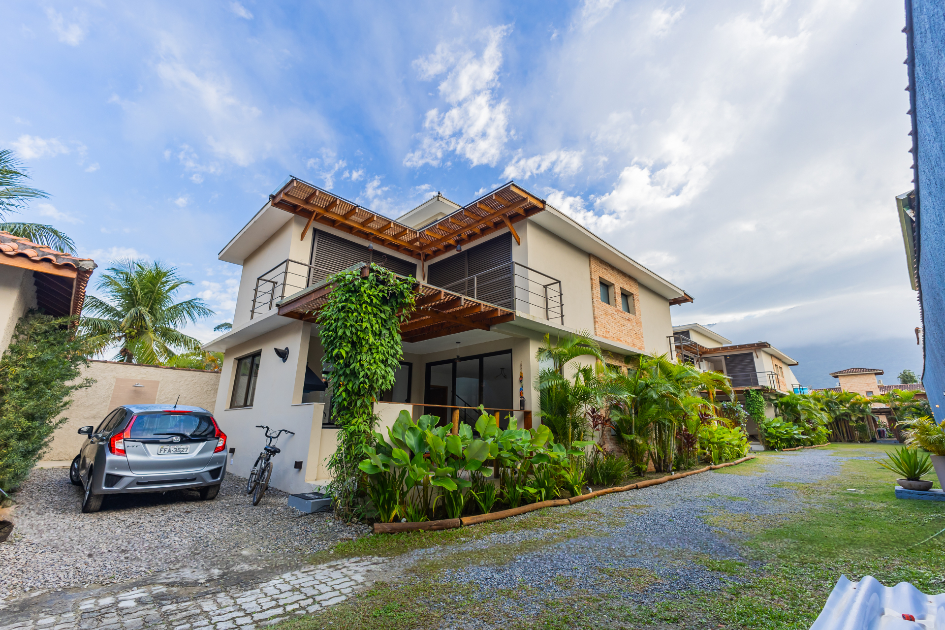 Fachada da casa com jardim tropical e céu azul