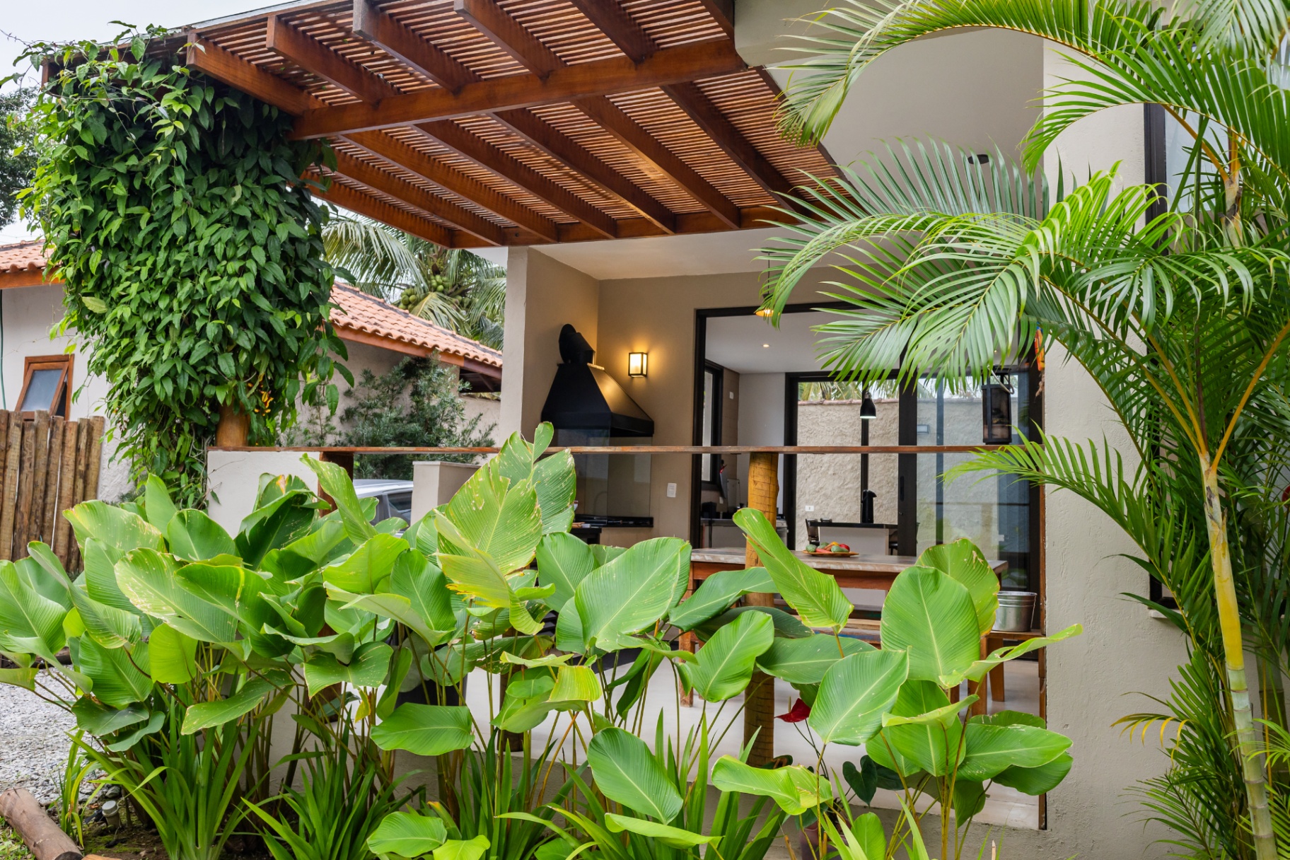 Área externa com pergolado e vegetação tropical